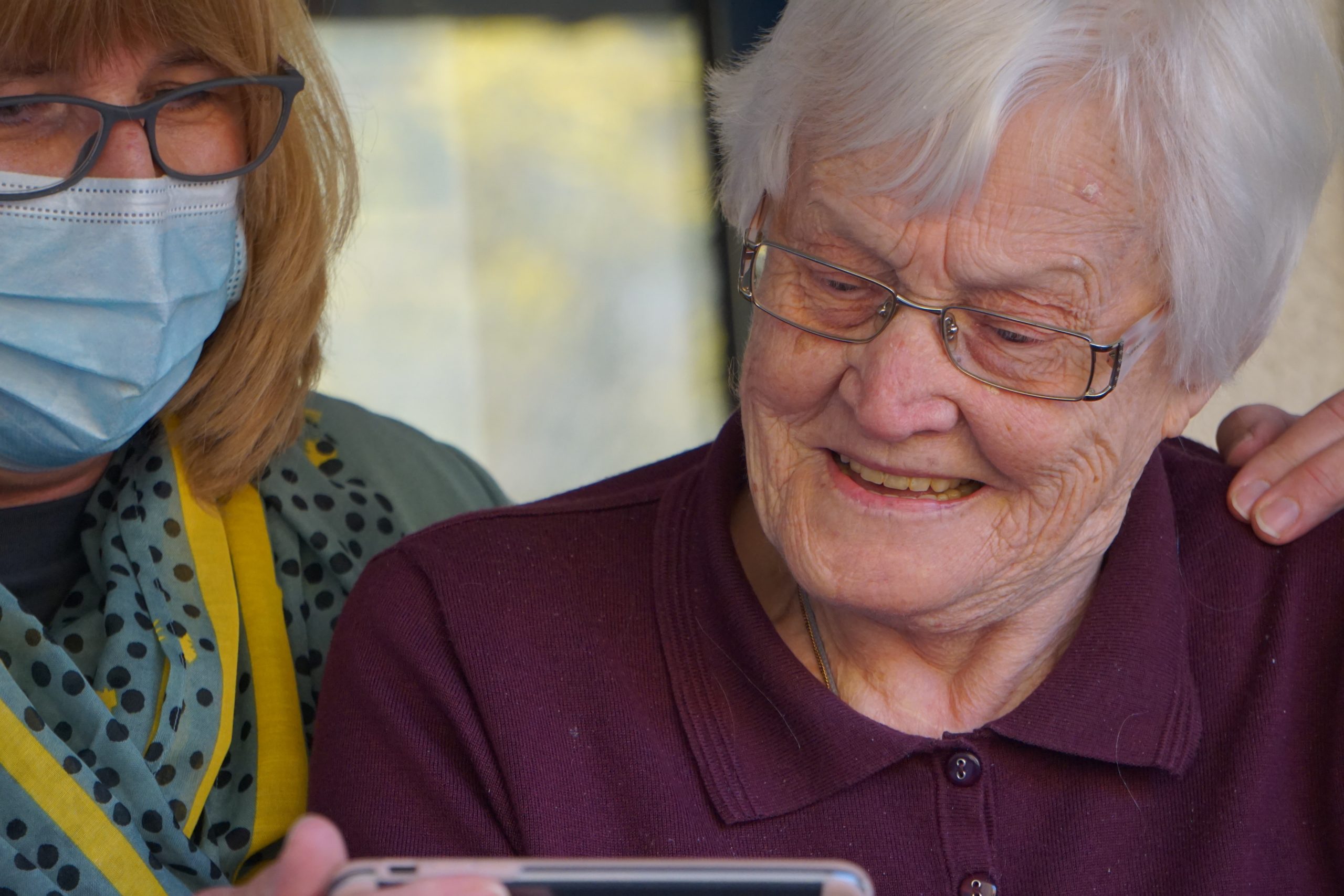 georg-arthur-pflueger-eO_JhqabBY0-unsplash A home health aide looks at a phone with an elderly woman