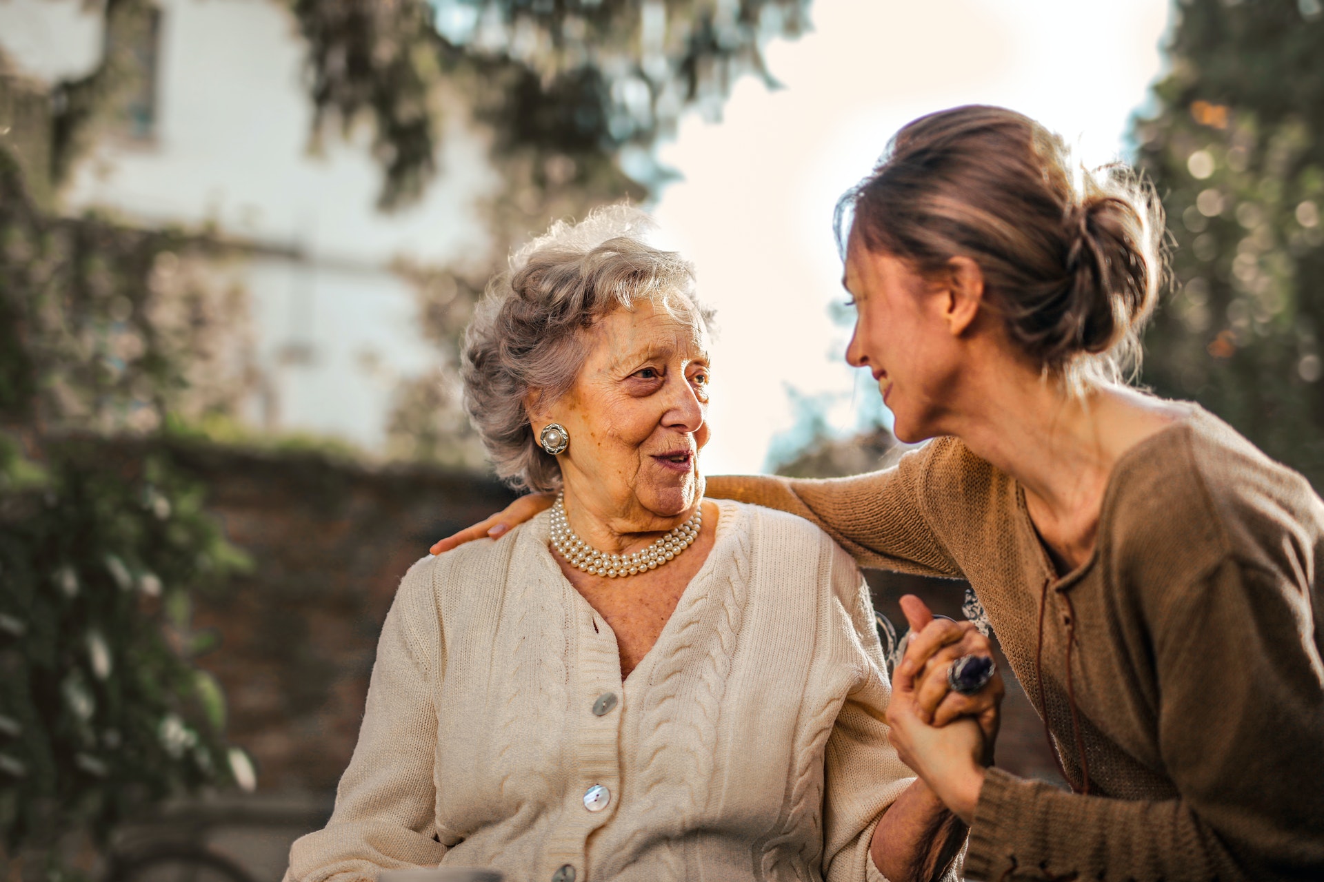 pexels-andrea-piacquadio-3768131 A woman sits with her arm around an elderly woman as they talk