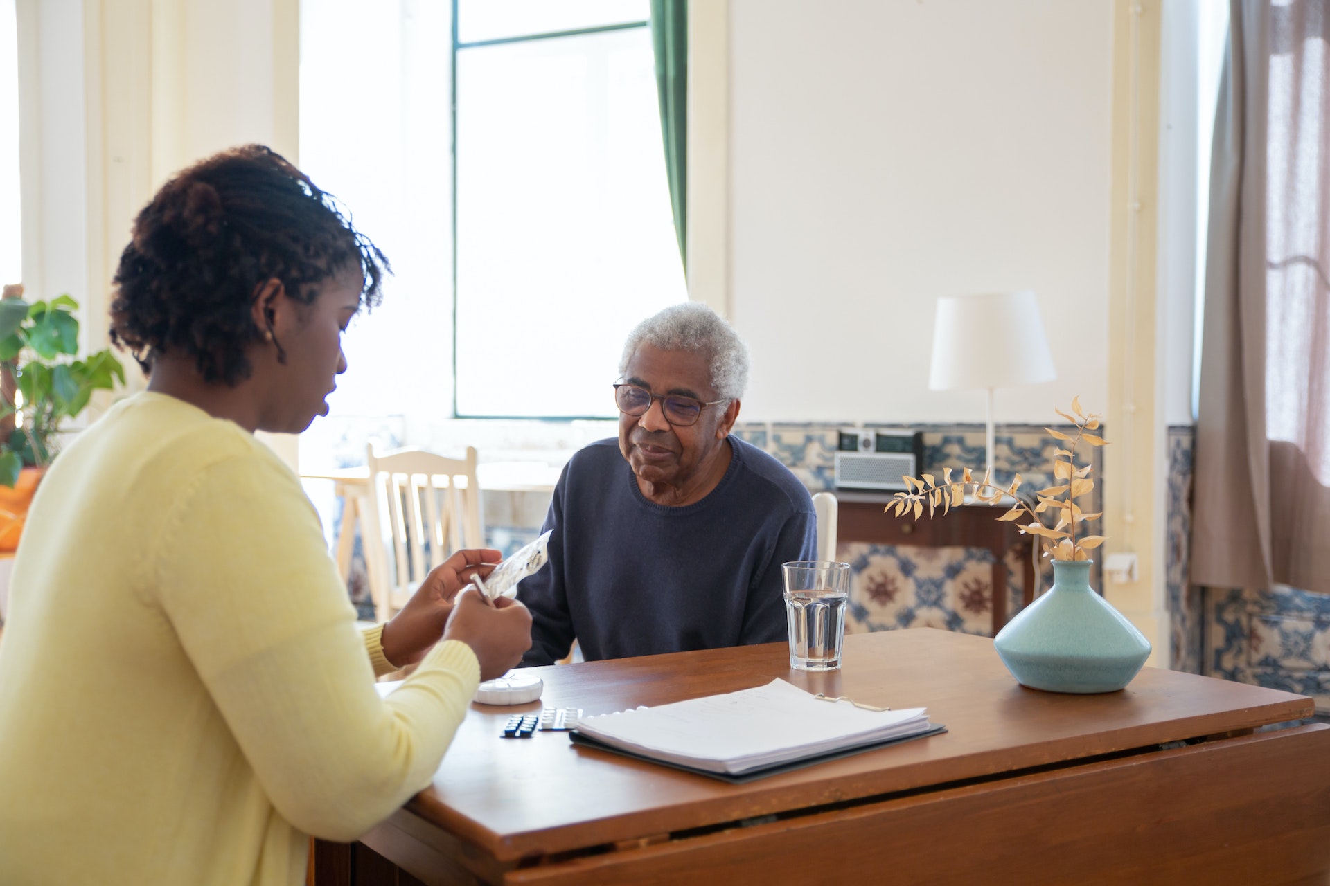 A woman helps an elderly man with his medication