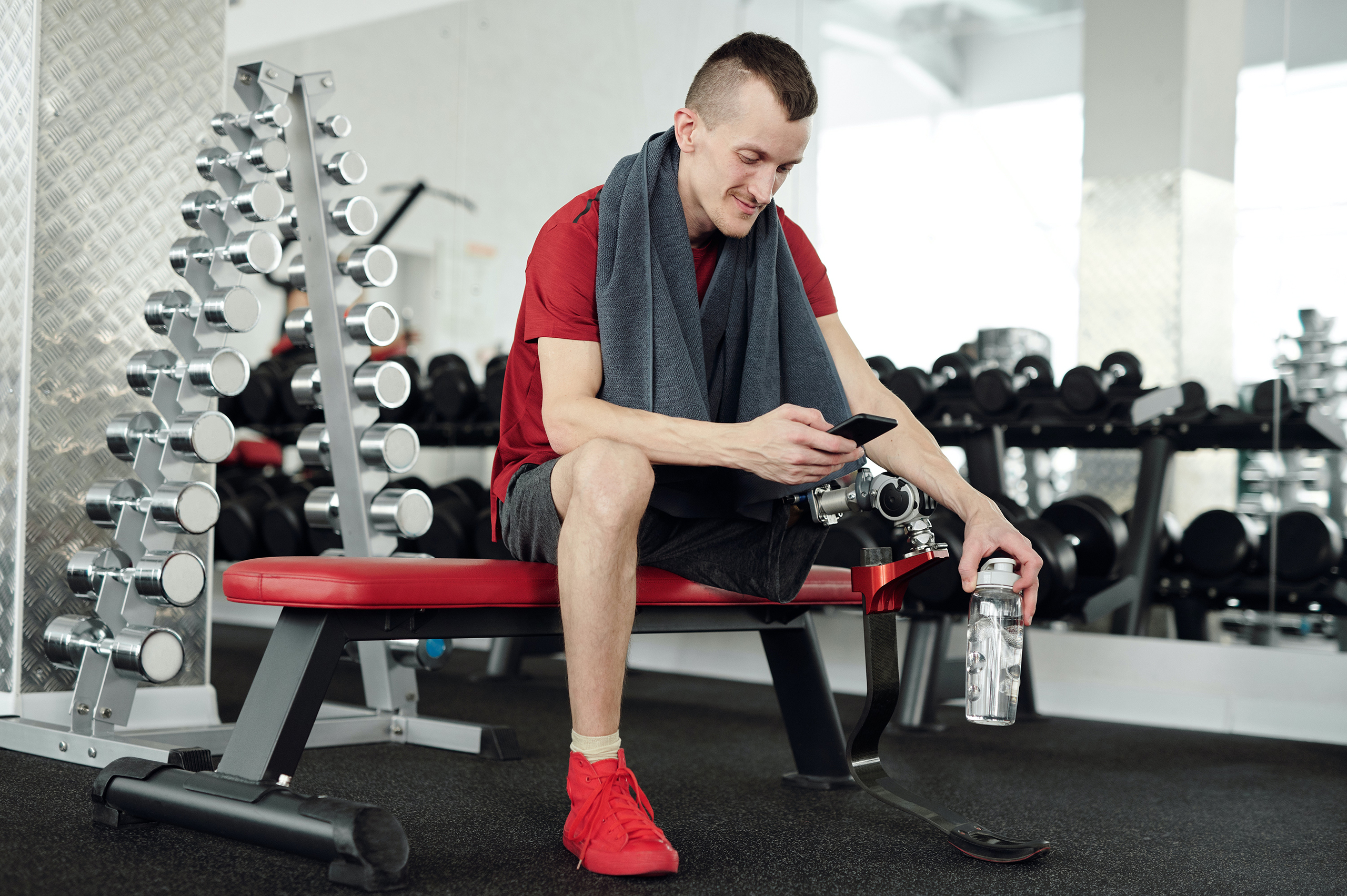 pexels-shotpot-4047241 A man with a prosthetic leg looks at his phone at the gym